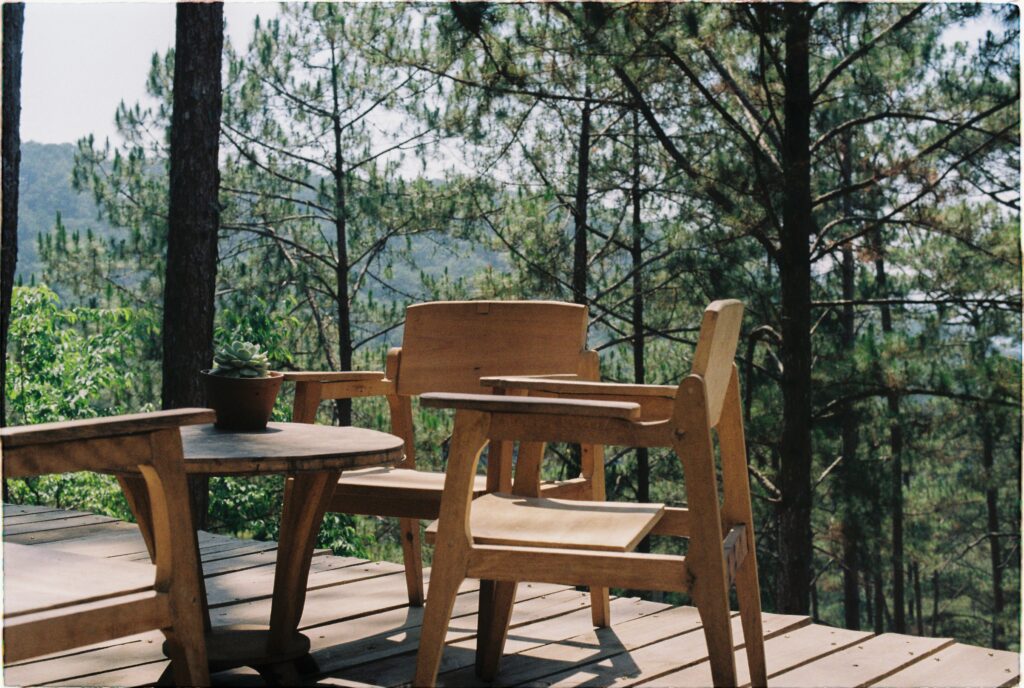 Wooden patio with chairs and table overlooking a lush forest, perfect for relaxation.